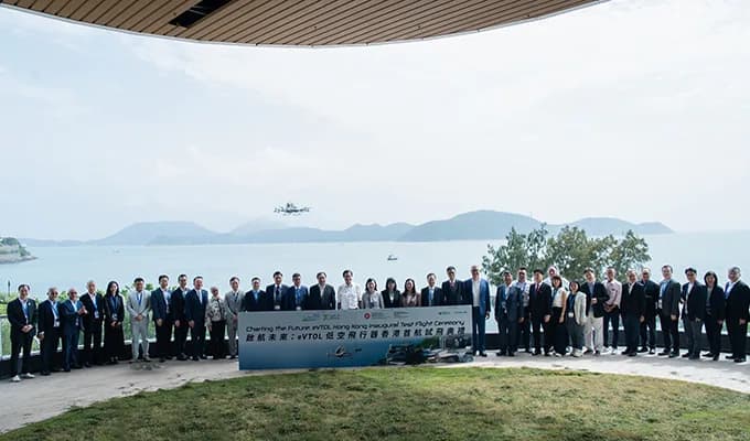 Deltagare står framför Hongkongs kust medan EHang EH216-S flyger i bakgrunden